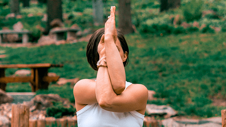 a woman doing yoga amidst lush green surrounding