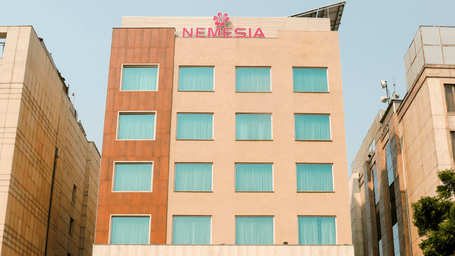 Facade of the Nemesia City Center in Gurugram featuring the hotel's entrance and its surrounding greenery.