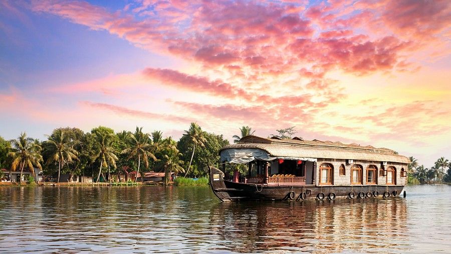 A boathouse floating in a small river surrounded by palm trees. At the horizon there is a sky in turned into evening hues.