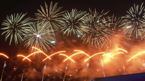 A night-time view of a fireworks display with golden trails and bursts above a dark silhouette.