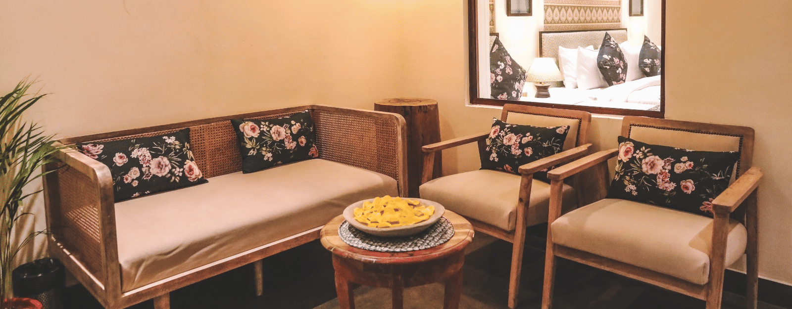 Small seating area with a sofa, chairs, wall frames, and a window at Beelwa Palace, Jaipur