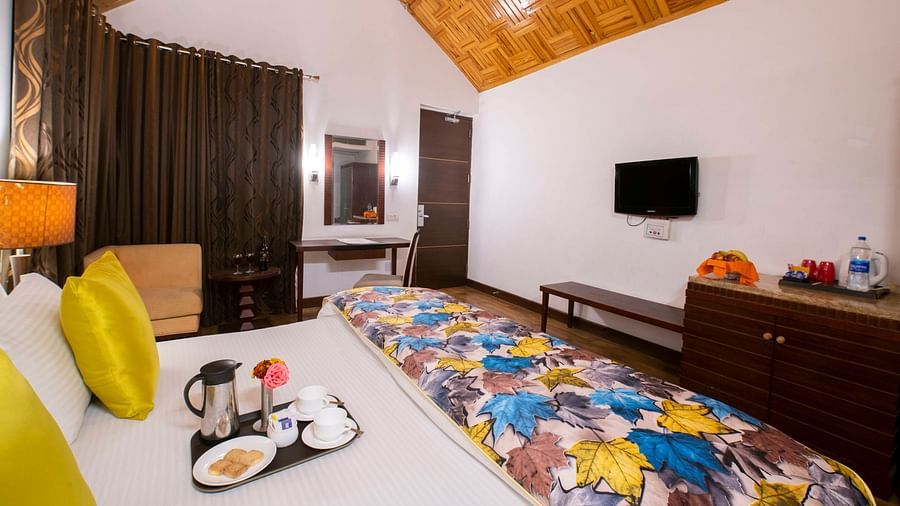 an image of the interior of cottage featuring a bed, television and wooden ceiling at Mastiff Grand, Manali