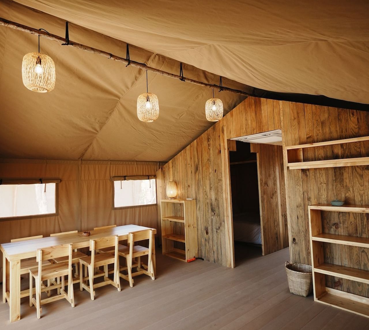 The dining area inside the Peaceful Tent at WoCAL Retreat Ke Ga, featuring a long handcrafted table, cane lighting, and natural interiors designed for intimate meals and shared moments.