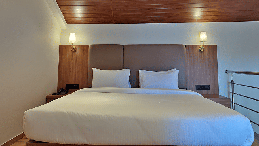 Bedroom with a double bed, wooden headboard, bedside lights, and railing