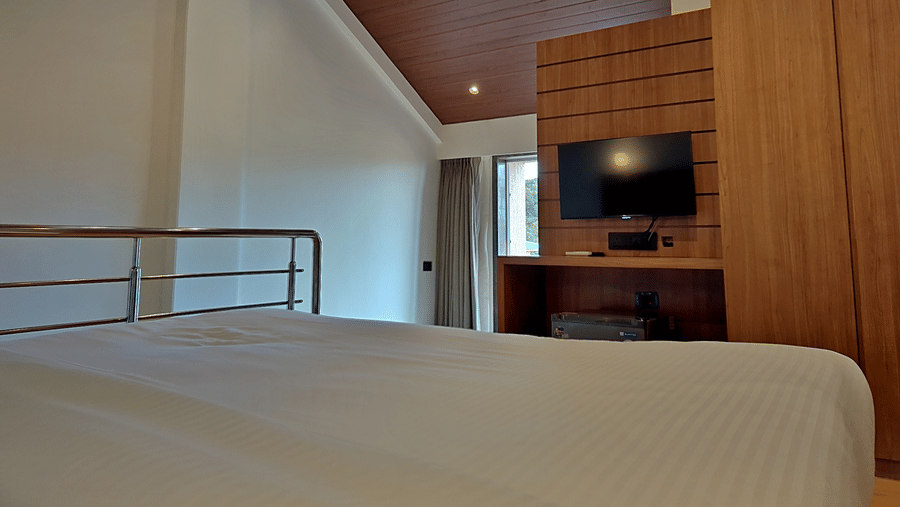 Bedroom with a double bed, television, wooden furnishings, and railing