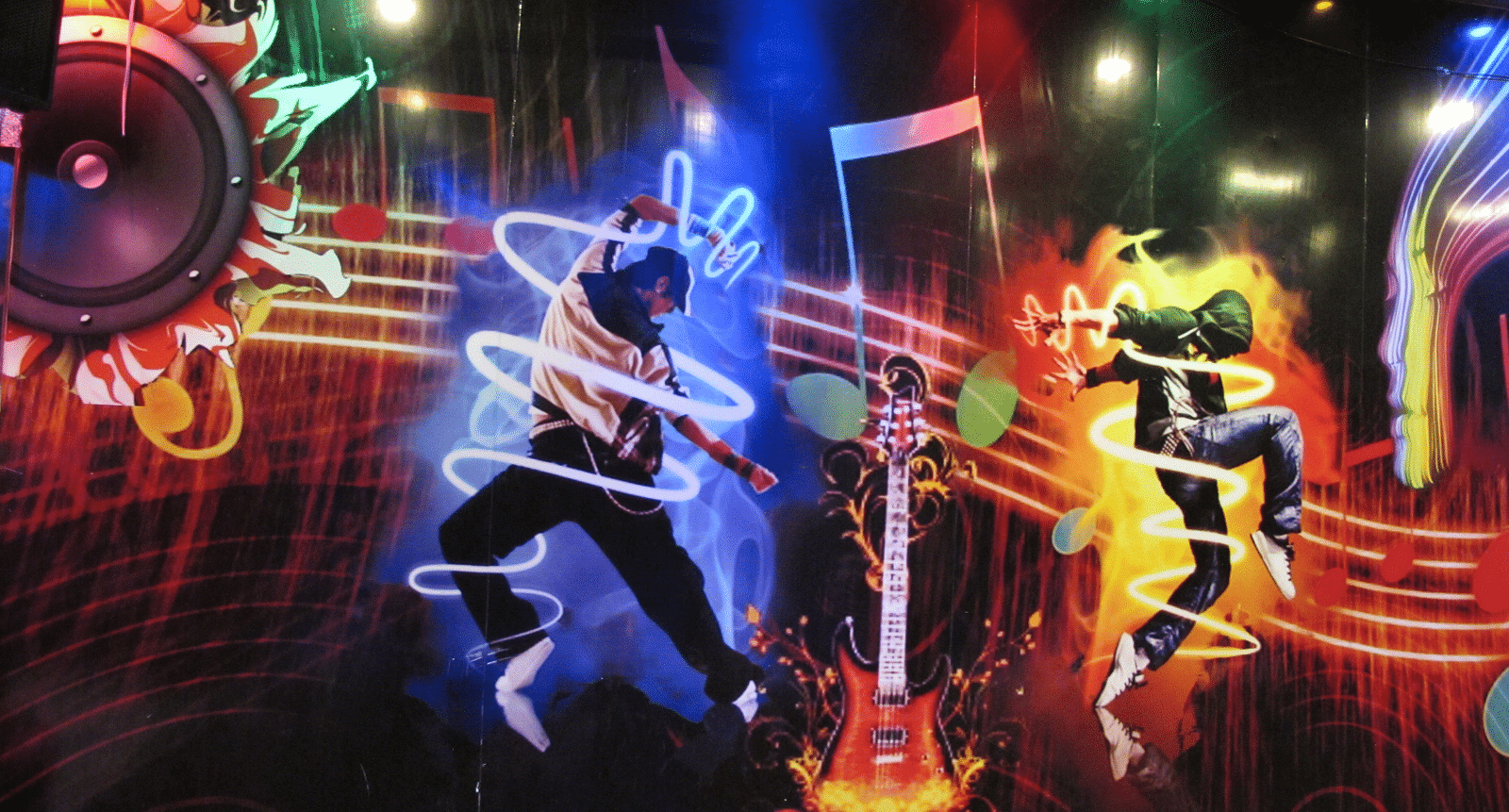 A close-up view of the wall mural, showcasing energetic dancers and dynamic light effects - TGI Apple Inn, Jaipur 