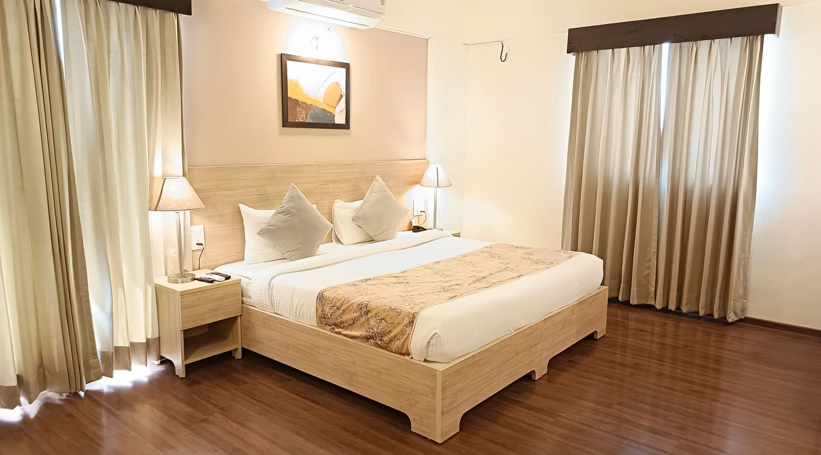 Plush bed on a well-furnished floor under warm lighting with two lamps on the nightstands on both sides of the bed inside premium studio at Starlit Suites, Shirdi