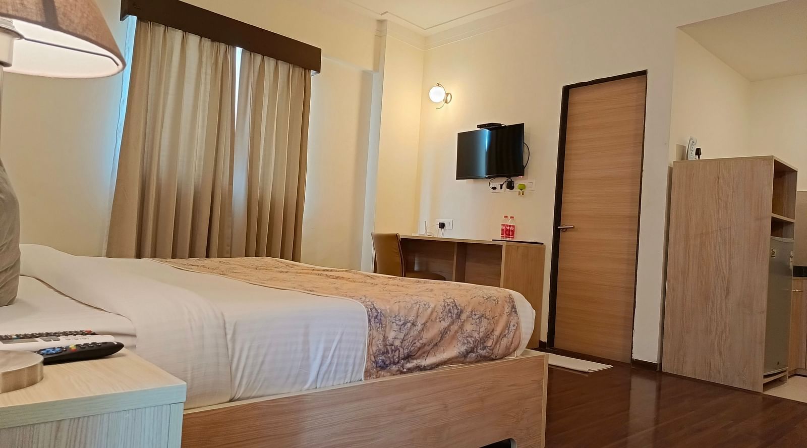 Plush bed facing the TV mounted on the wall inside premium studio - Starlit Suites, Shirdi