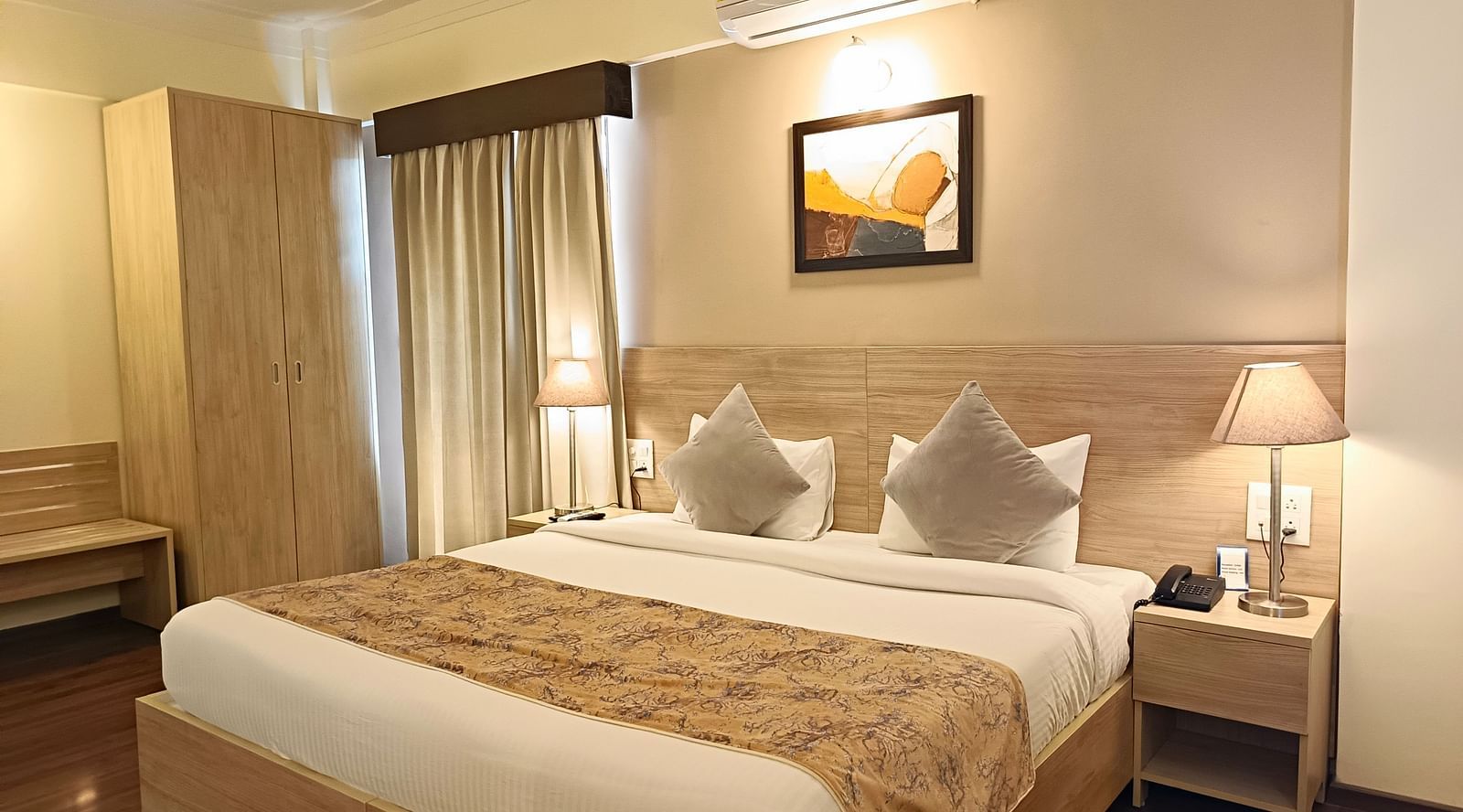 Plush bed with a couple of lamps lit on both sides on the nightstands inside warmly lit premium studio at Starlit Suites, Shirdi