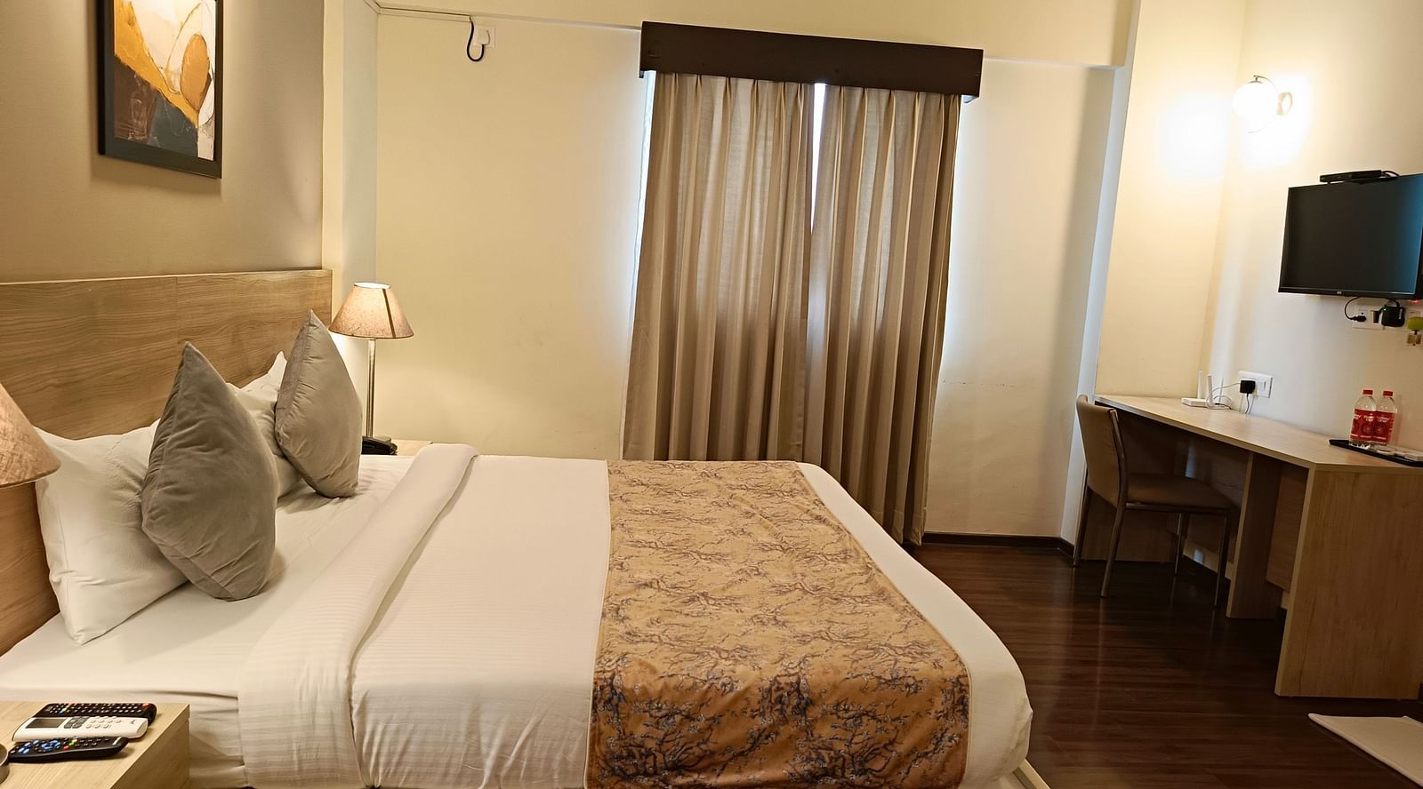 Plush bed with a TV opposite it mounted on the wall over the work desk inside premium studio at Starlit Suites, Shirdi