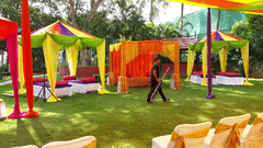 A lawn with colorful fabric canopies and chairs arranged below at the best resort in Bangalore | Ramanashree California Resort