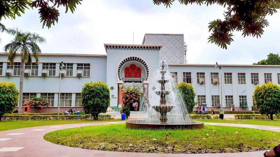fountain in front of a white building with a tree in the foreground and blue sky in the background - Chunda Hotels