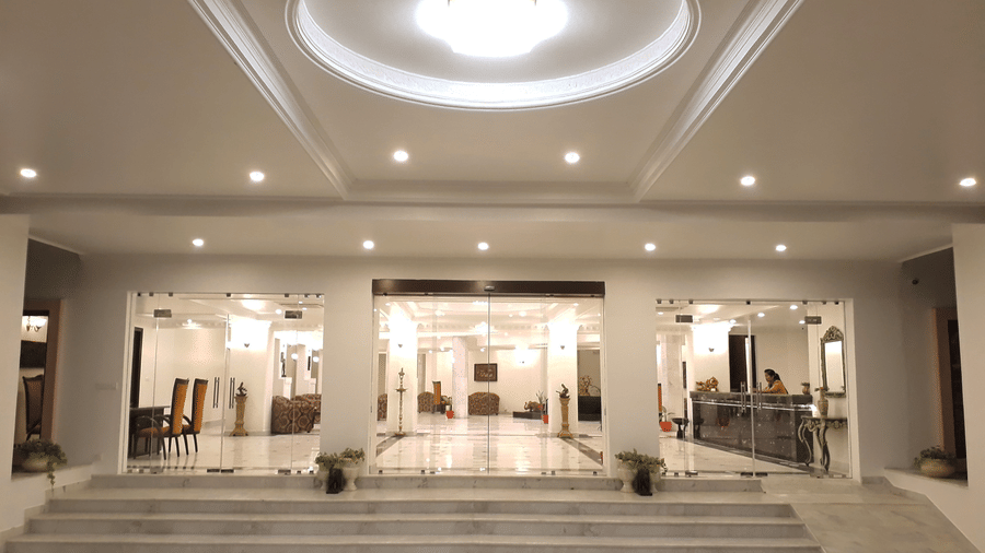 A well-lit hotel entrance with stairs and a chandelier at AS Hotels, Khajuraho.