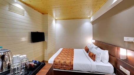 An image of a room with a queen size bed, TV and room amenities like tea coffee maker - Sumitel Vista TV Tower
