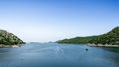 Expansive Jaisamand Lake, Alwar, under a clear blue sky with a few boats on the water