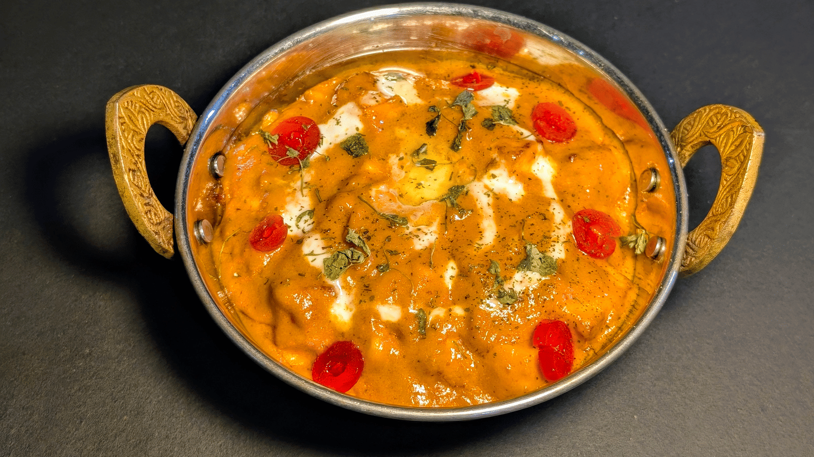 Creamy paneer butter masala garnished with herbs and cherry tomatoes at Dip Holidays.