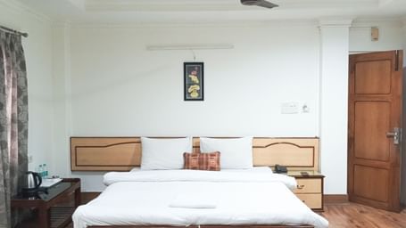 Deluxe Triple Room A.C. at Ecotel Vinayak, Siliguri with twin beds, bright lighting, wooden floor, and classic décor.  