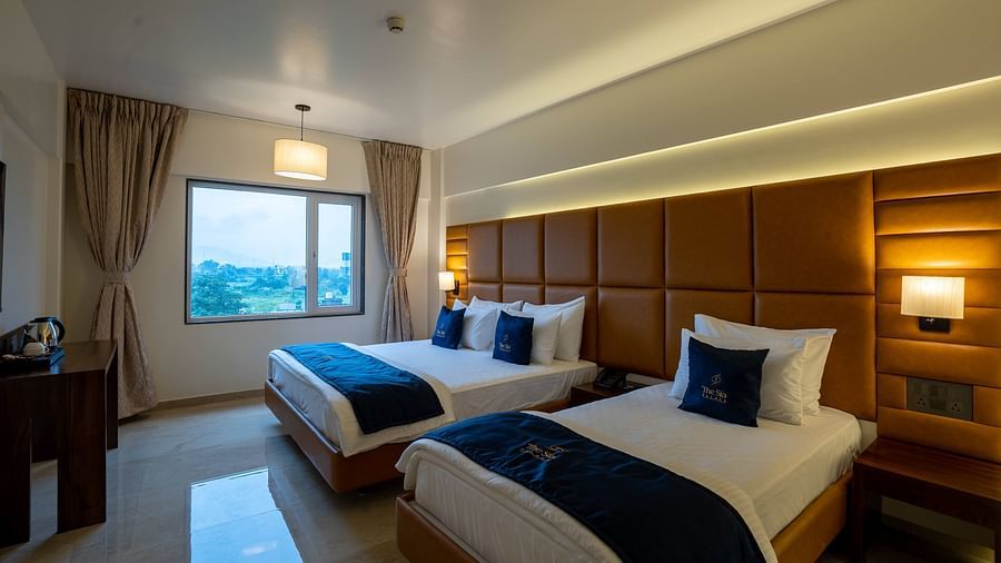 Side view of two beds in Family Premium with bedside tables scenic view from windows with curtains - Mastiff Grand - The Sia Palace Suites Banquets Khopoli