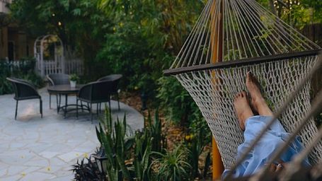 Hammock placed in a stone-paved garden area with surrounding greenery at Karma Chalets.