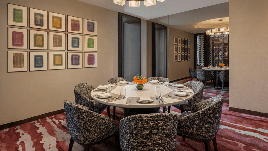 Executive Lounge with a round dining table, framed art wall and chandelier at The Residency Signature Madurai.