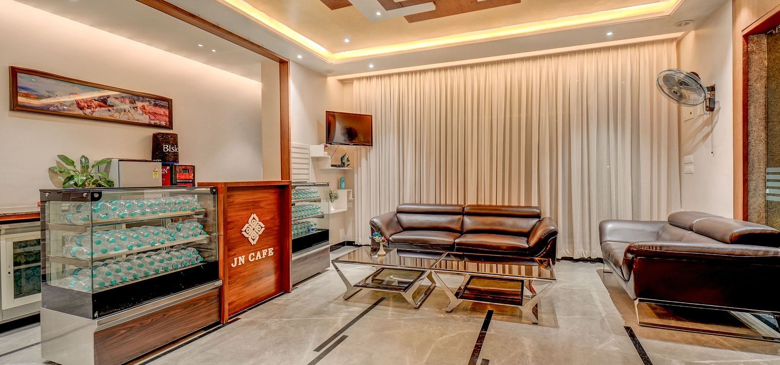 The reception area at Harigovinda's JNStay, with a desk to the side and a cushioned sofa with a table in front