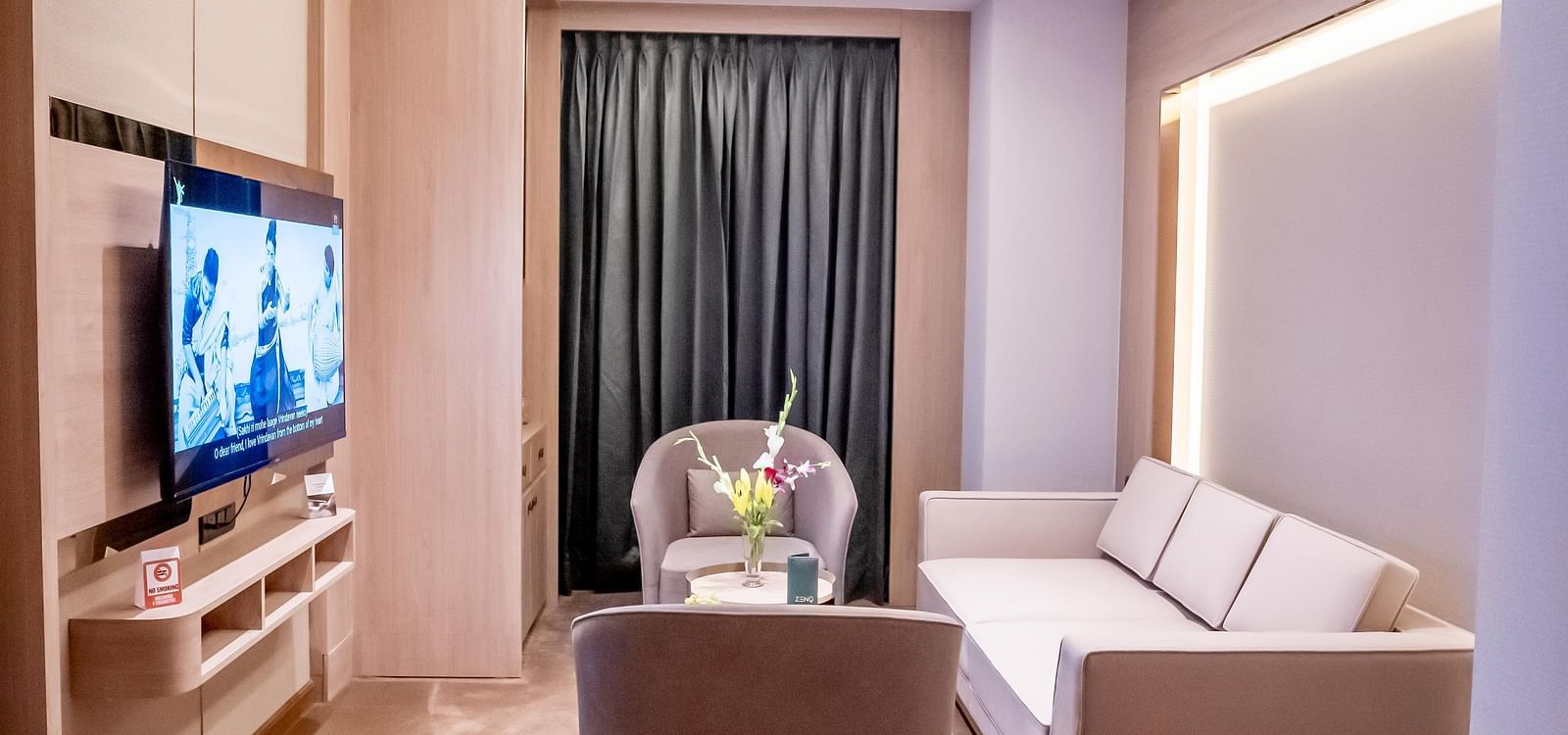 Living area with seating, TV and a window with a curtain in the background at ASTER GRAND BY ZENQ SAKET.