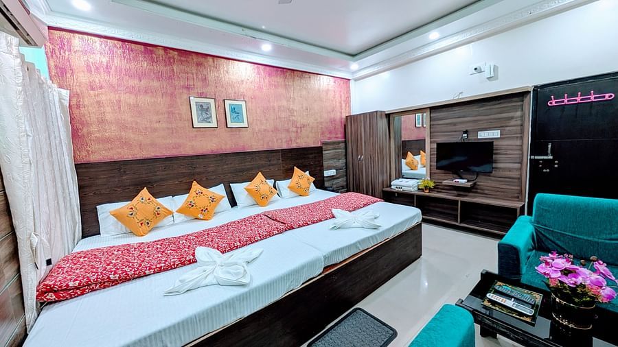 An image of a bedroom featuring four beds, a seating area with sofa and centre table, a flat TV screen, a wardrobe and dressing tale at Rangamati Garden Resort