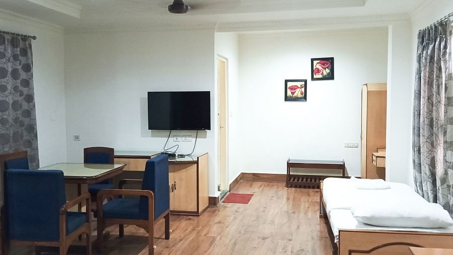 Deluxe Triple Room A.C. at Ecotel Vinayak, Siliguri with twin beds, bright lighting, wooden floor, classic décor, and a comfortable living area. 