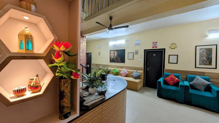 A resort reception lobby featuring decorative lit shelving, a reception desk, and comfortable teal sofas.