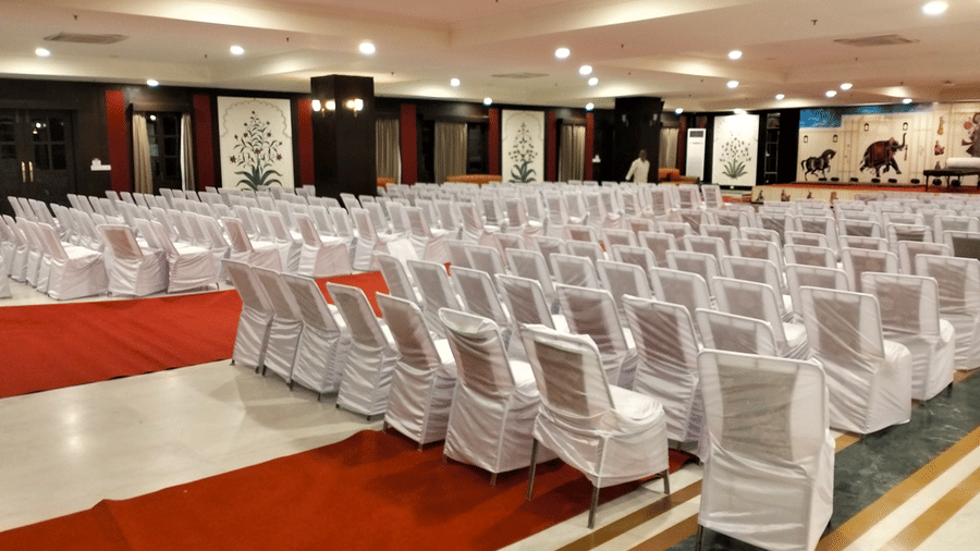 Raj Mahal hall filled with white-covered chairs arranged in rows facing a stage with a red carpet at Shri Vallabh Vilas Lords Plaza Nathdwara.