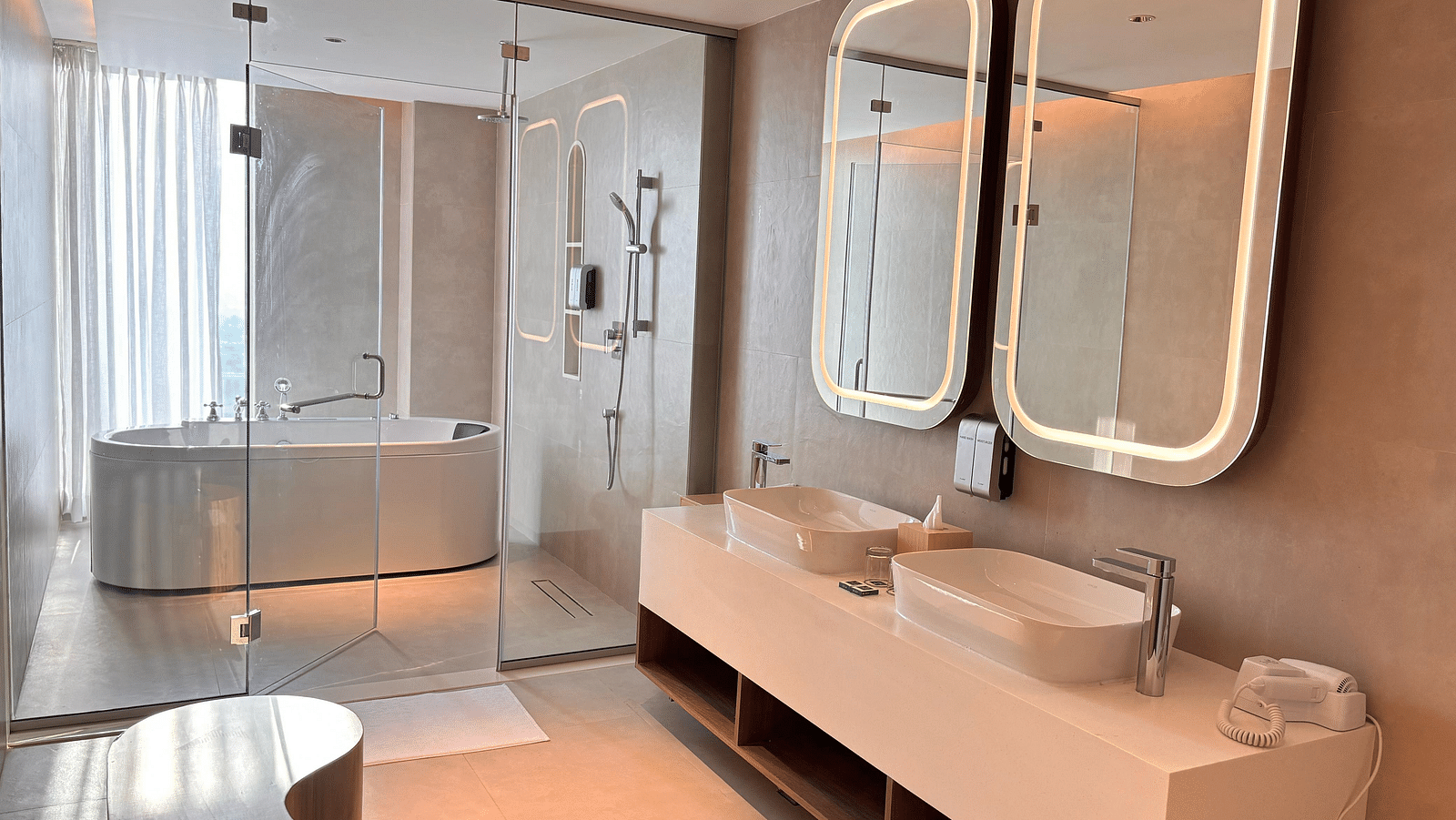 A bathroom at Swosti Premium Beach Resorts, Puri, with double sinks, mirrors, and a bathtub.