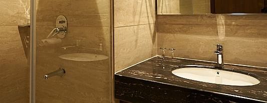 A modern bathroom featuring a glass-enclosed shower, sink, and mirror at The Hamuse Hotel, Kodaikanal.