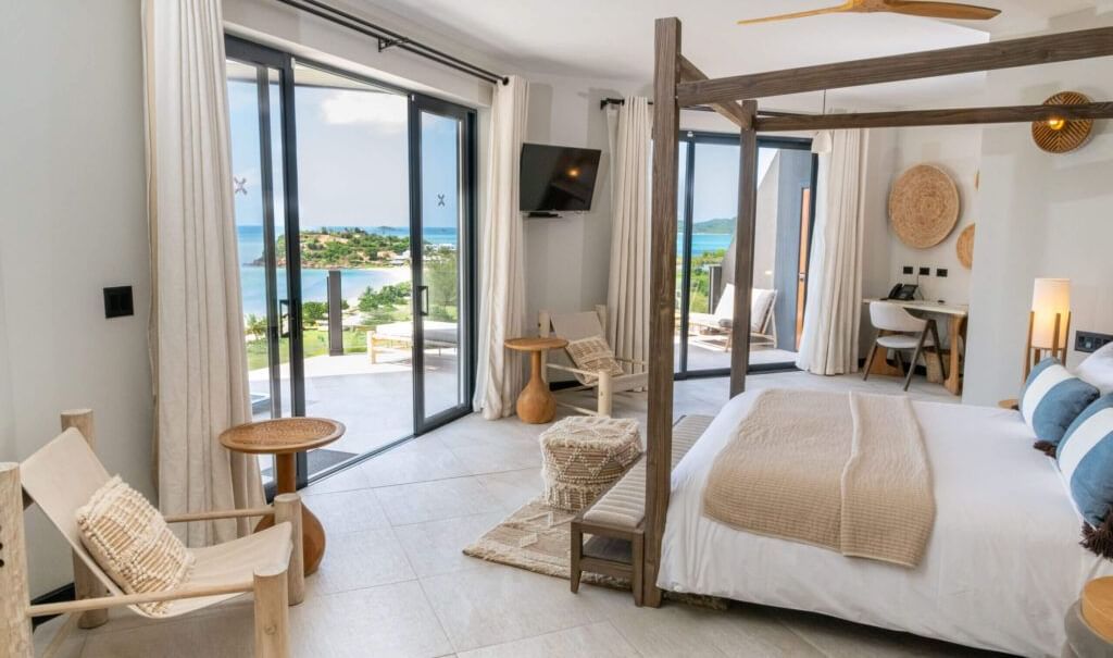 Spacious bedroom with canopy bed, seating area, and ocean view balcony at Tamarind Hills Resort and Villas - Antigua.