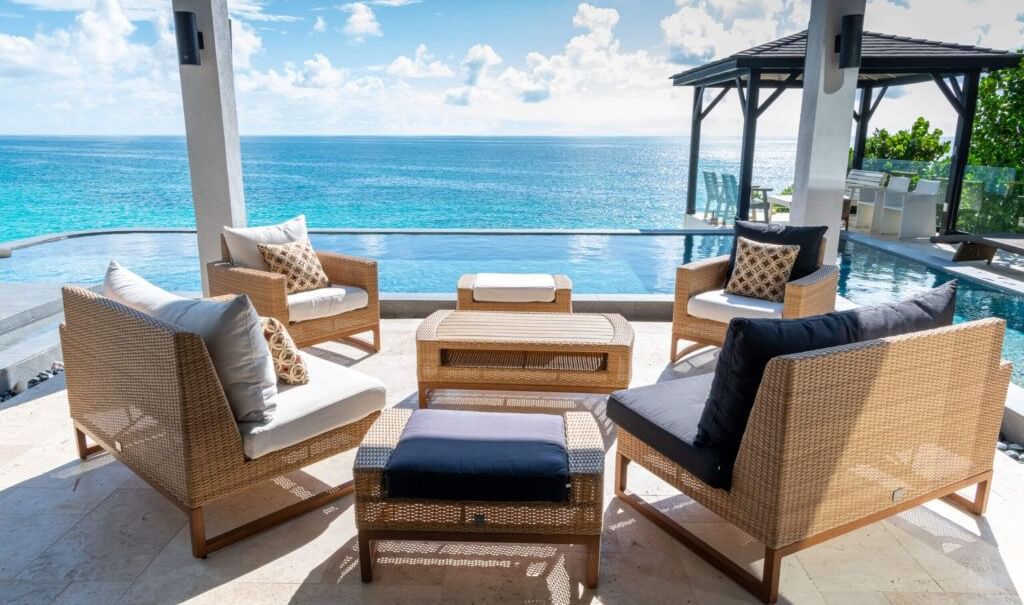 Outdoor lounge area with wicker seating overlooking the turquoise Caribbean Sea at Tamarind Hills Resorts and Villas.