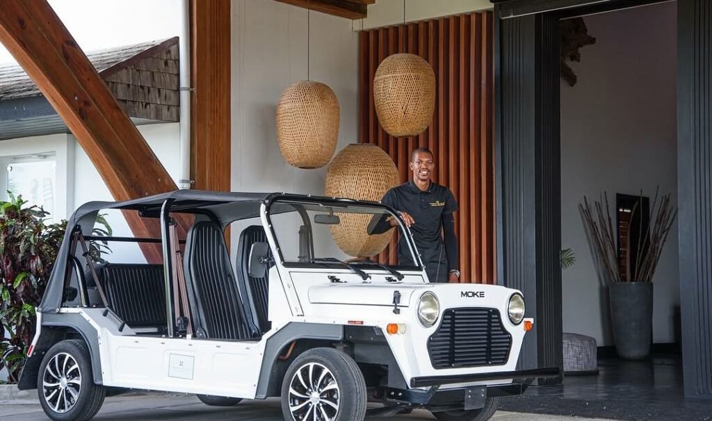 ChatGPT said: A white open-top electric vehicle parked near a stylish hotel entrance, with a staff member standing beside it - Tamarind Hills Resort and Villas - Antigua