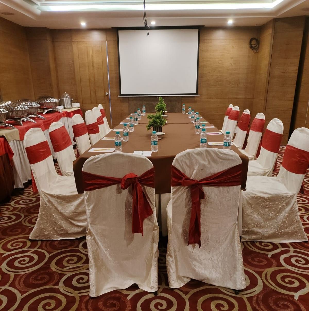 A conference room arranged for a meeting with red chairs and a patterned carpet - The President Hotel Jayanagar, Bangalore