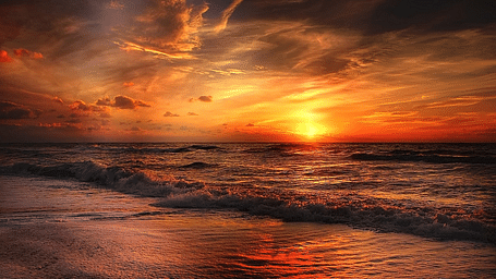 Stunning sunset over the beach with dark clouds painting the evening sky