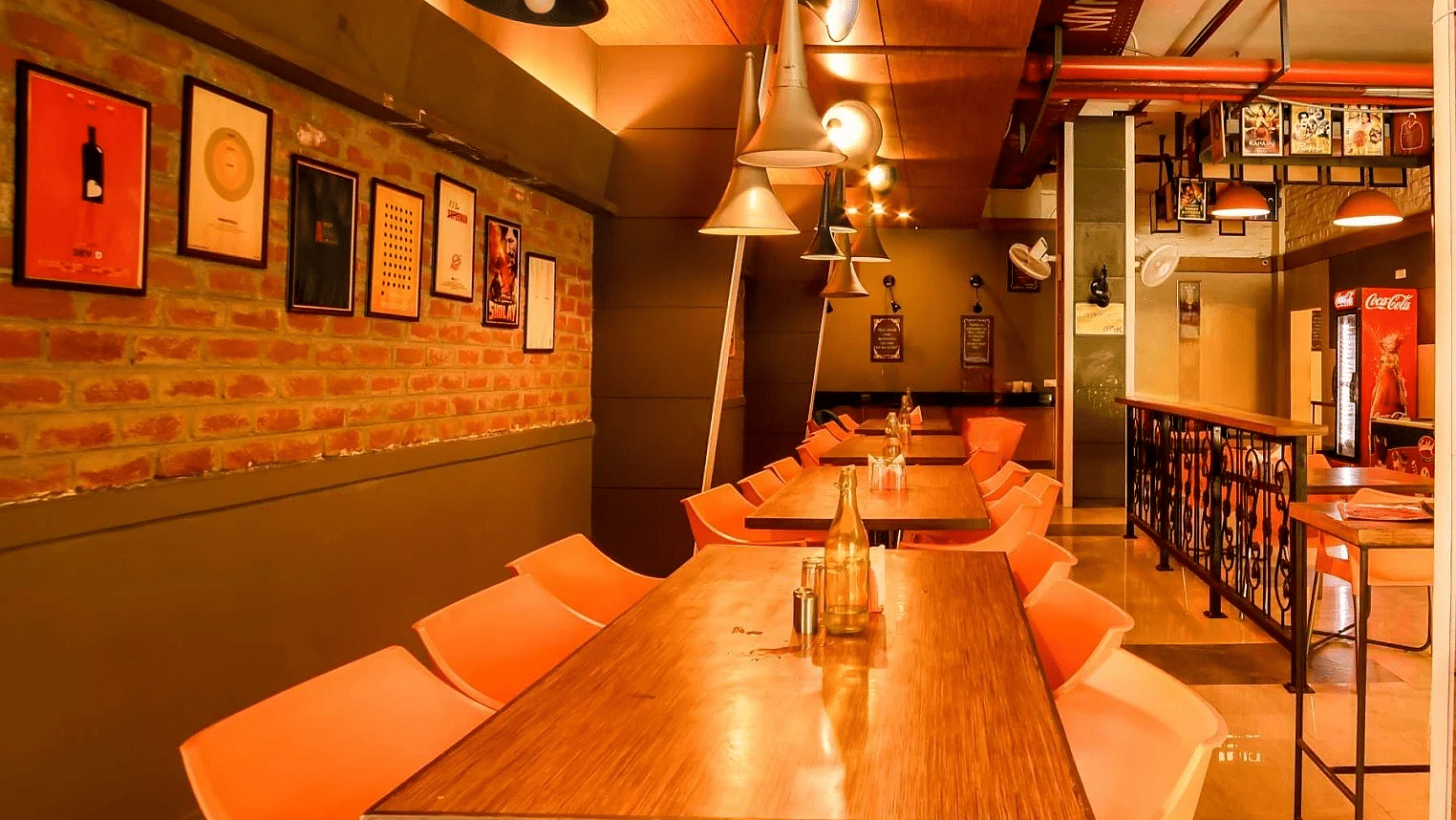 A contemporary hotel dining space with long wooden tables, modern chairs, and eclectic wall art creating a casual yet stylish ambiance.