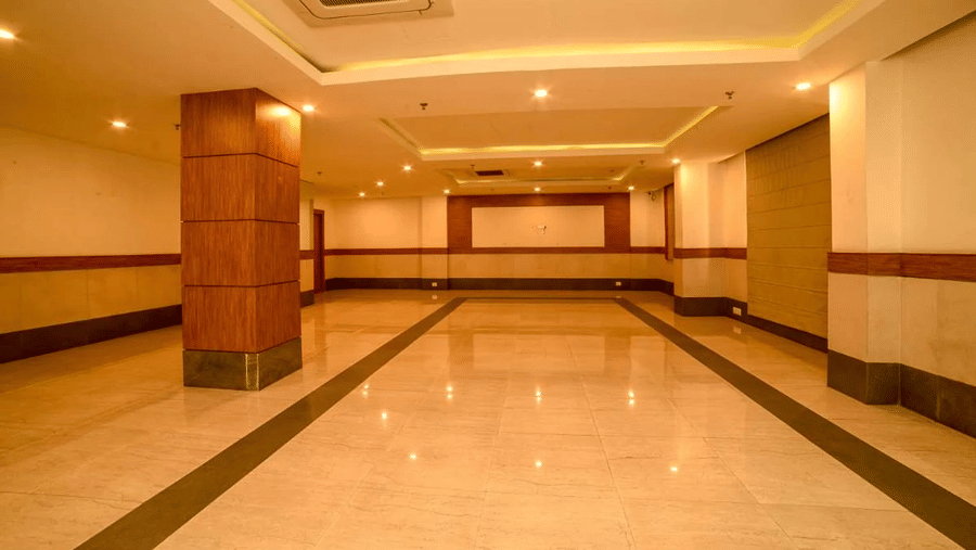 An image of a spacious banquet hall with installed lights in the ceiling - An image of a reception lobby featuring a reception desk , and a seating area for the guest - Max Hotel Jabalpur