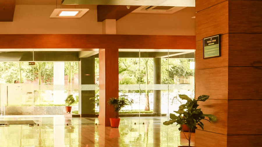 The front entrance of the hotel, featuring glass doors flanked by plants, leading into a shiny marble-floored lobby.