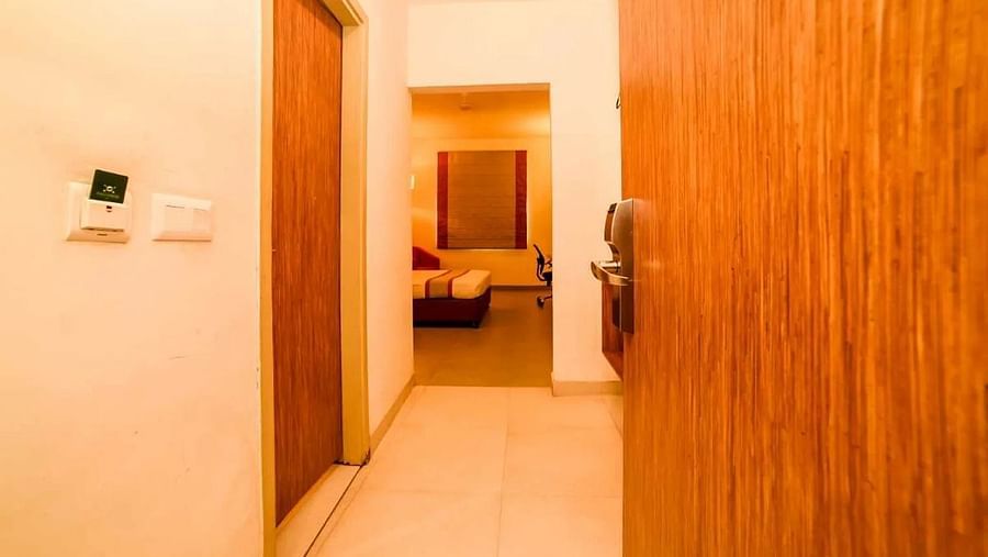 entrance of the Max Family Room with a wooden door opening into the corridor of the room - Max Hotel Jabalpur