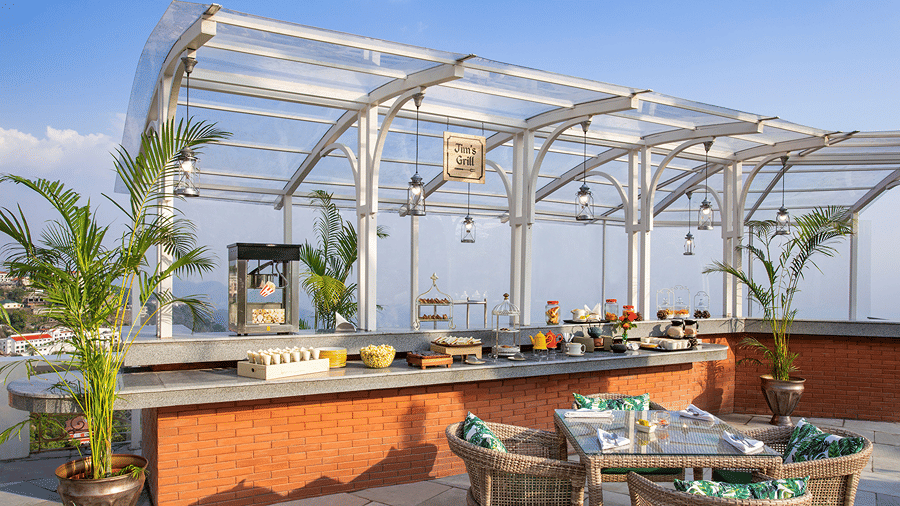 A open-air patio dining area with outdoor tables, chairs, and buffet counters at Ramada by Wyndham Mussoorie Mall Road.