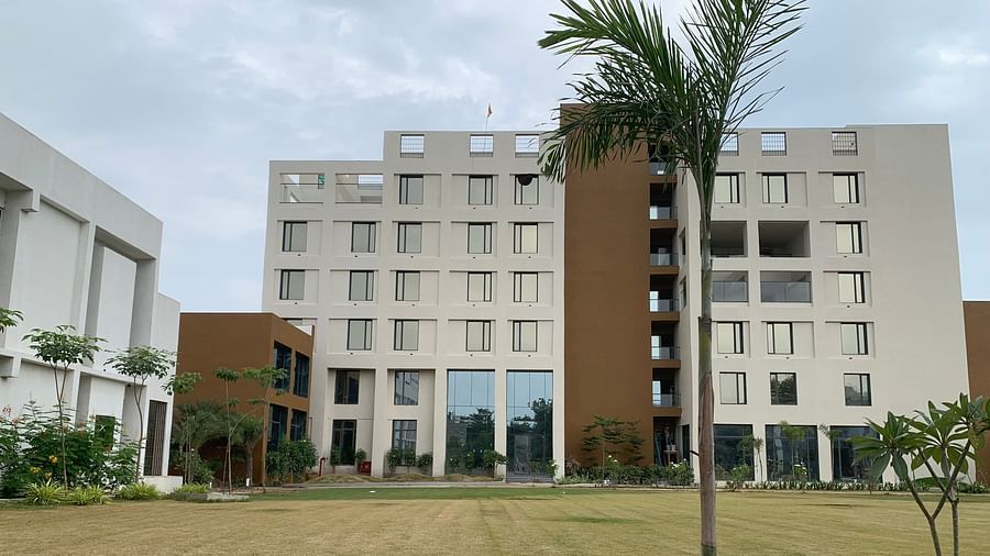 A front view of the facade of Pride Resort Ambaji with some trees in the picture around it