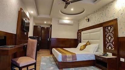 A spacious hotel room with a king size bed, two armchairs, a coffee table, a desk | DLS La Serene Manali