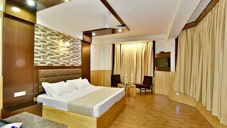 A room at DLS Hotel Devlok, Manali with a double bed, a coffee table set up and wooden flooring