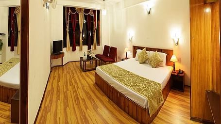 A room at DLS Hotel Devlok, Manali with a double bed, side tables, a wardrobe and wooden flooring