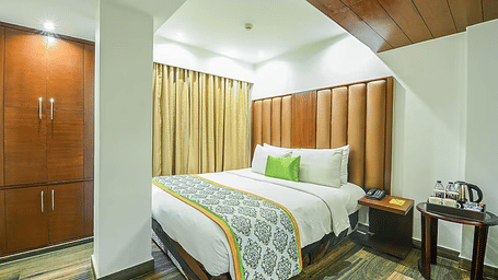 A cosy guest room featuring a tall padded leather headboard, a bed with a teal patterned runner, and elegant wooden wardrobes - Flute Boutique By Hotel 91, Jaipur
