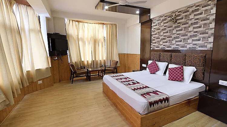 A view of a room at DLS Hotel Devlok, Manali with a double bed, a television and large windows