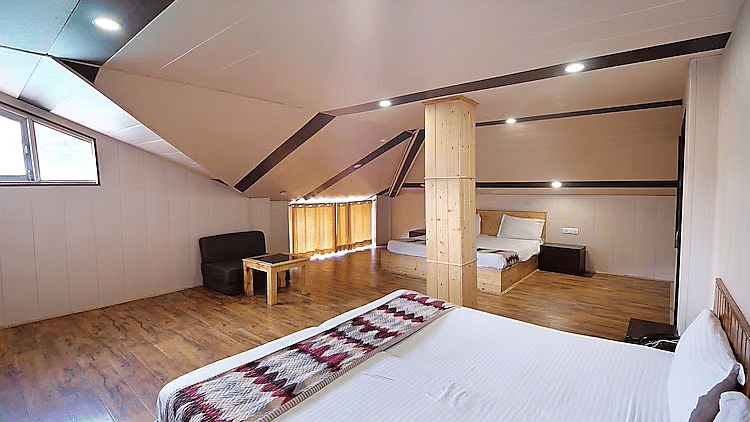 A room at DLS Hotel Devlok, Manali with a double bed and a sofa chair and a coffee table placed in front of it