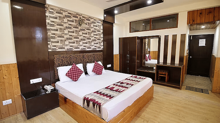 A view of a room at DLS Hotel Devlok, Manali with a double bed, side tables, a wardrobe and a dressing mirror